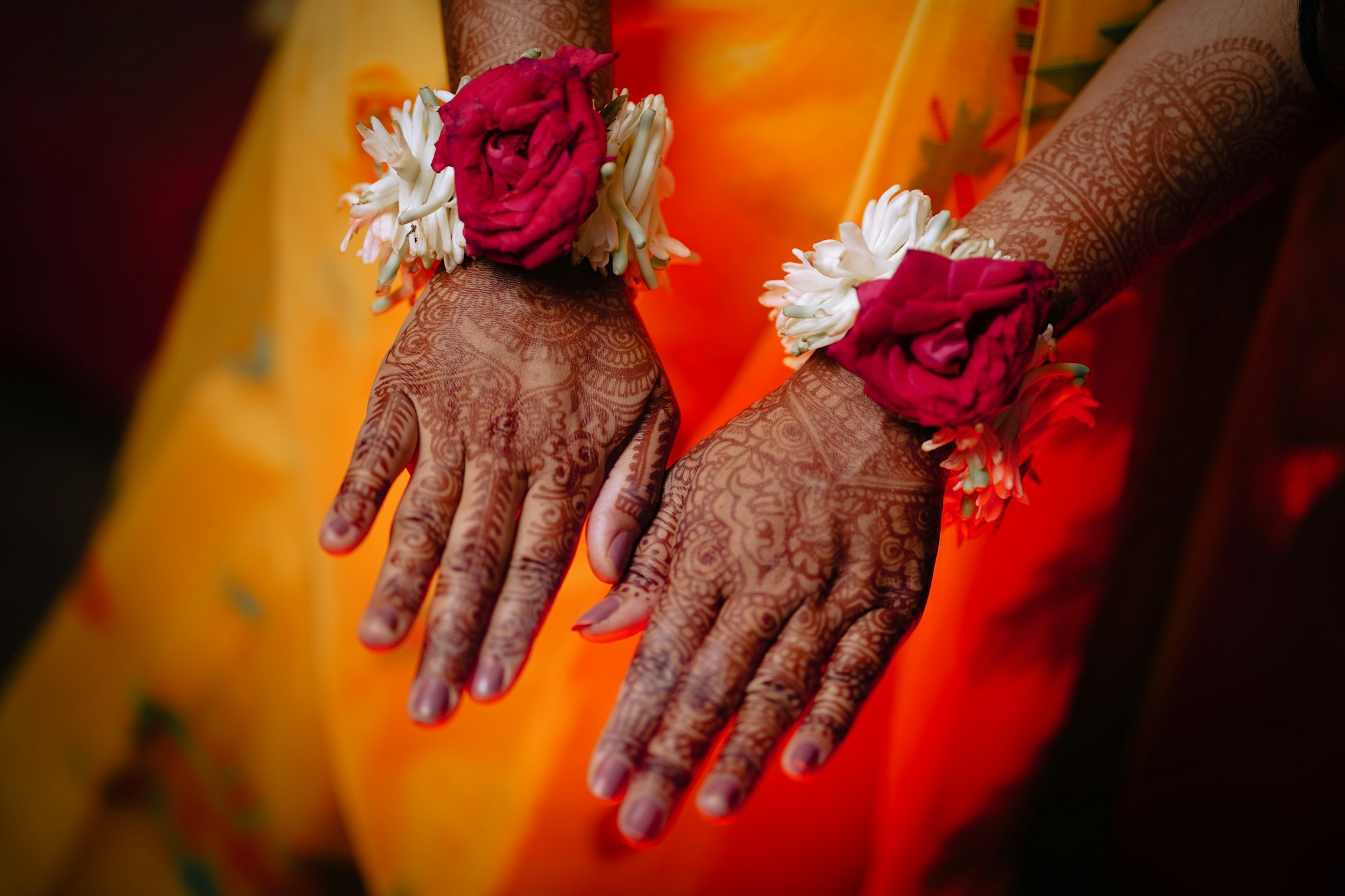 Hands decorated with intricate mehendi and floral bracelets