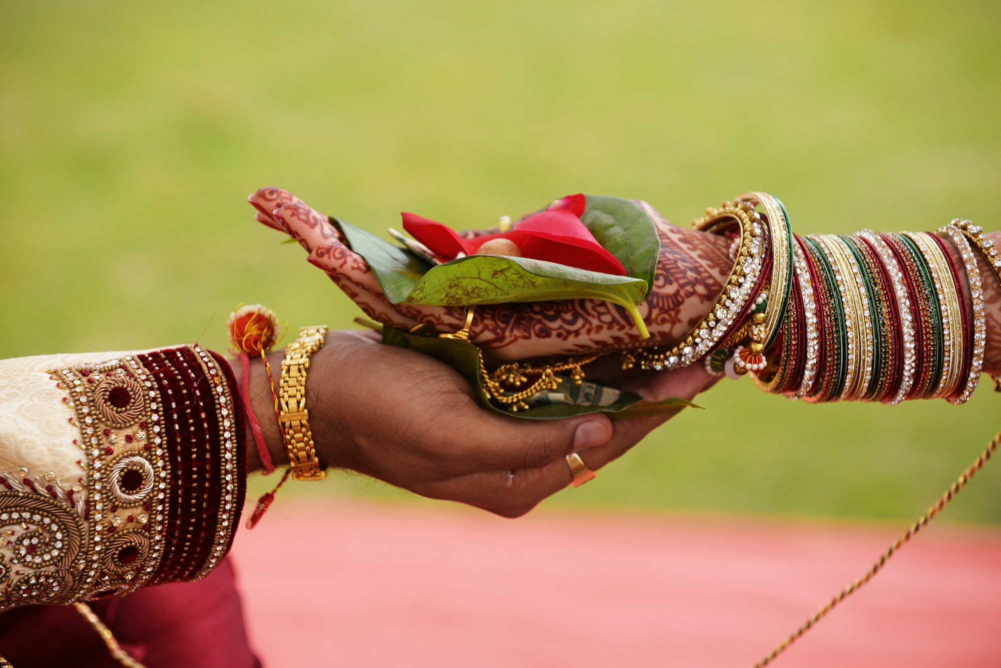 A bride's hennaed hand with bangles placed in the groom's palm during a wedding ritual